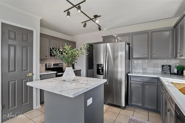 a kitchen with stainless steel appliances granite countertop a kitchen island a stove a refrigerator and a sink