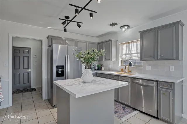 a kitchen with stainless steel appliances kitchen island a refrigerator sink and cabinets