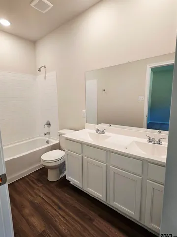 a bathroom with a double vanity sink a toilet and a bathtub