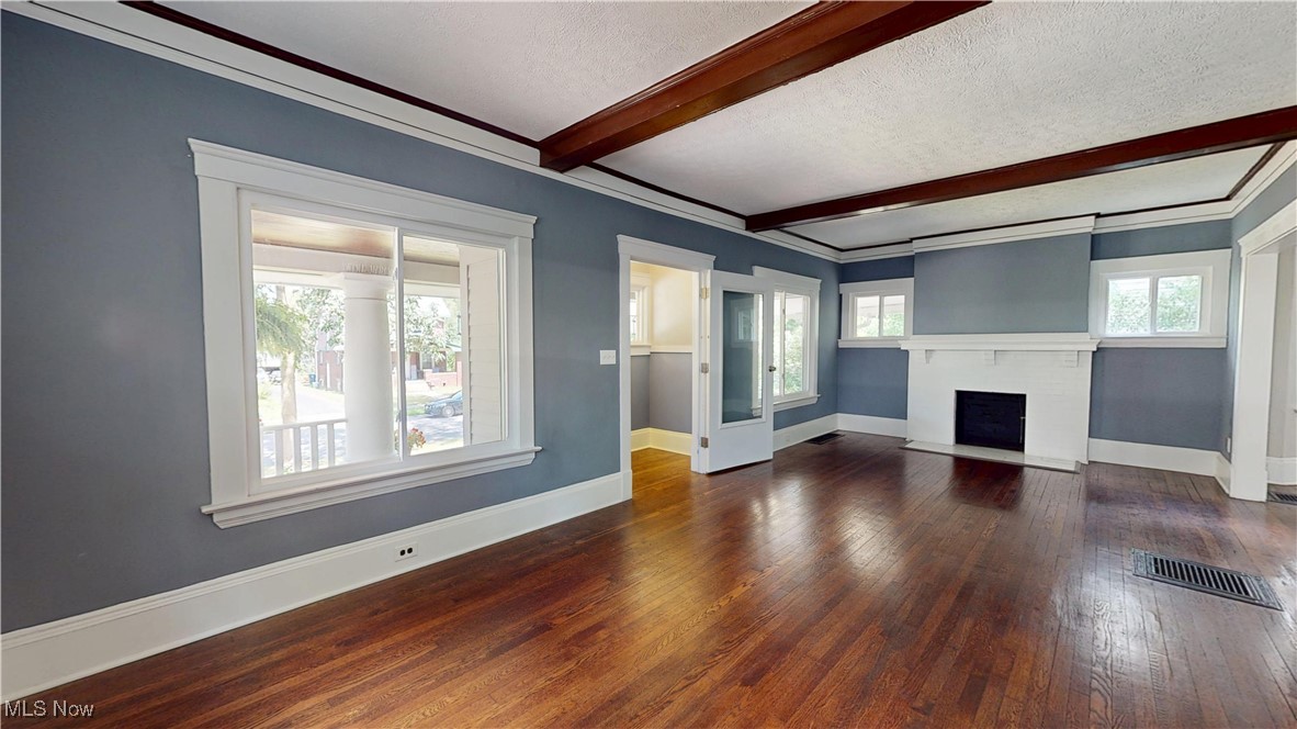 3174 Oak Road Cleveland, OH 44118 - Photo 6 of 33 Unfurnished living room with wood-type flooring, beamed ceiling, a textured ceiling, a fireplace with flush hearth, and crown molding