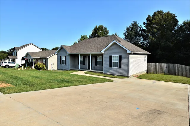 a front view of a house with a yard and trees