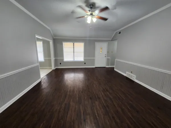 an empty room with wooden floor and windows