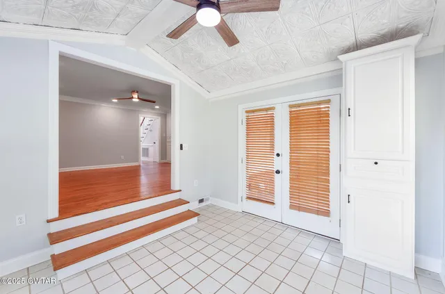 en empty room with window and a chandelier fan