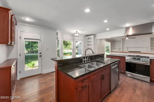 a kitchen with kitchen island granite countertop a sink stove and wooden floor