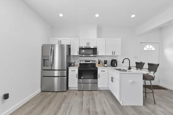 a kitchen with stainless steel appliances a refrigerator stove a sink and white cabinets