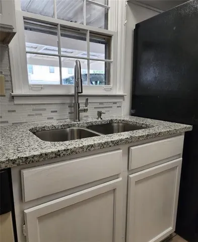 a kitchen with granite countertop white cabinets and a sink
