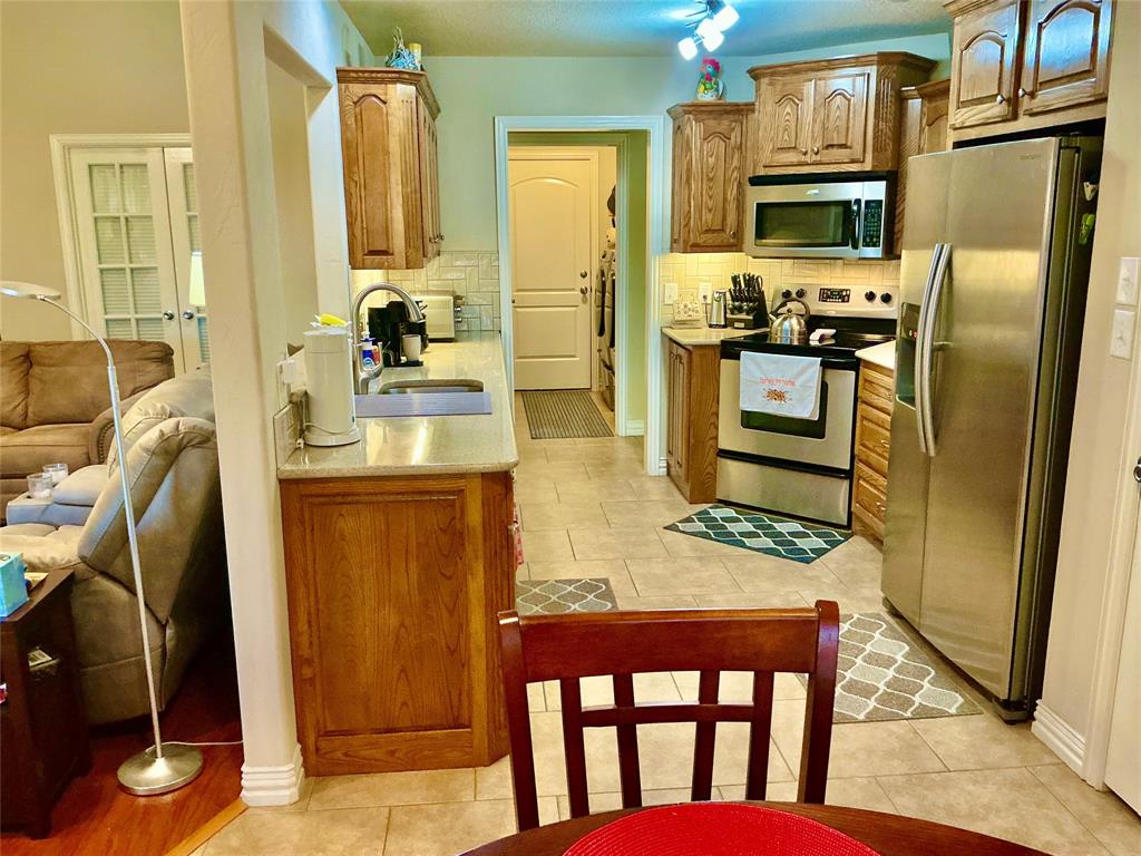 312 McAfee Street Mabank, TX 75147 - Photo 22 of 40 a kitchen with stainless steel appliances granite countertop a refrigerator a stove top oven and a dining table