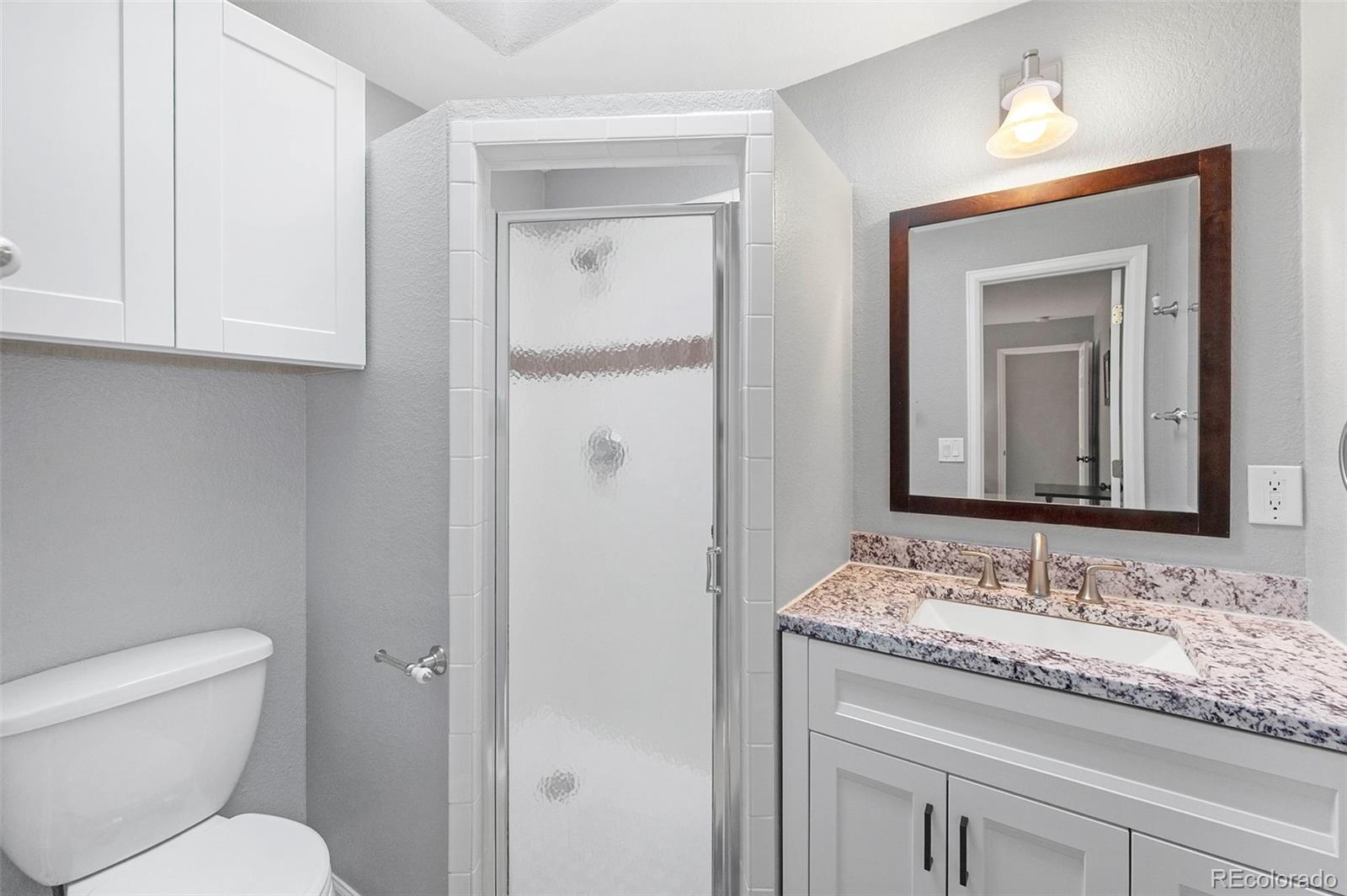 809 5th Street, Unit 201 Golden, CO 80403 - Photo 11 of 32 a bathroom with a granite countertop sink toilet and mirror