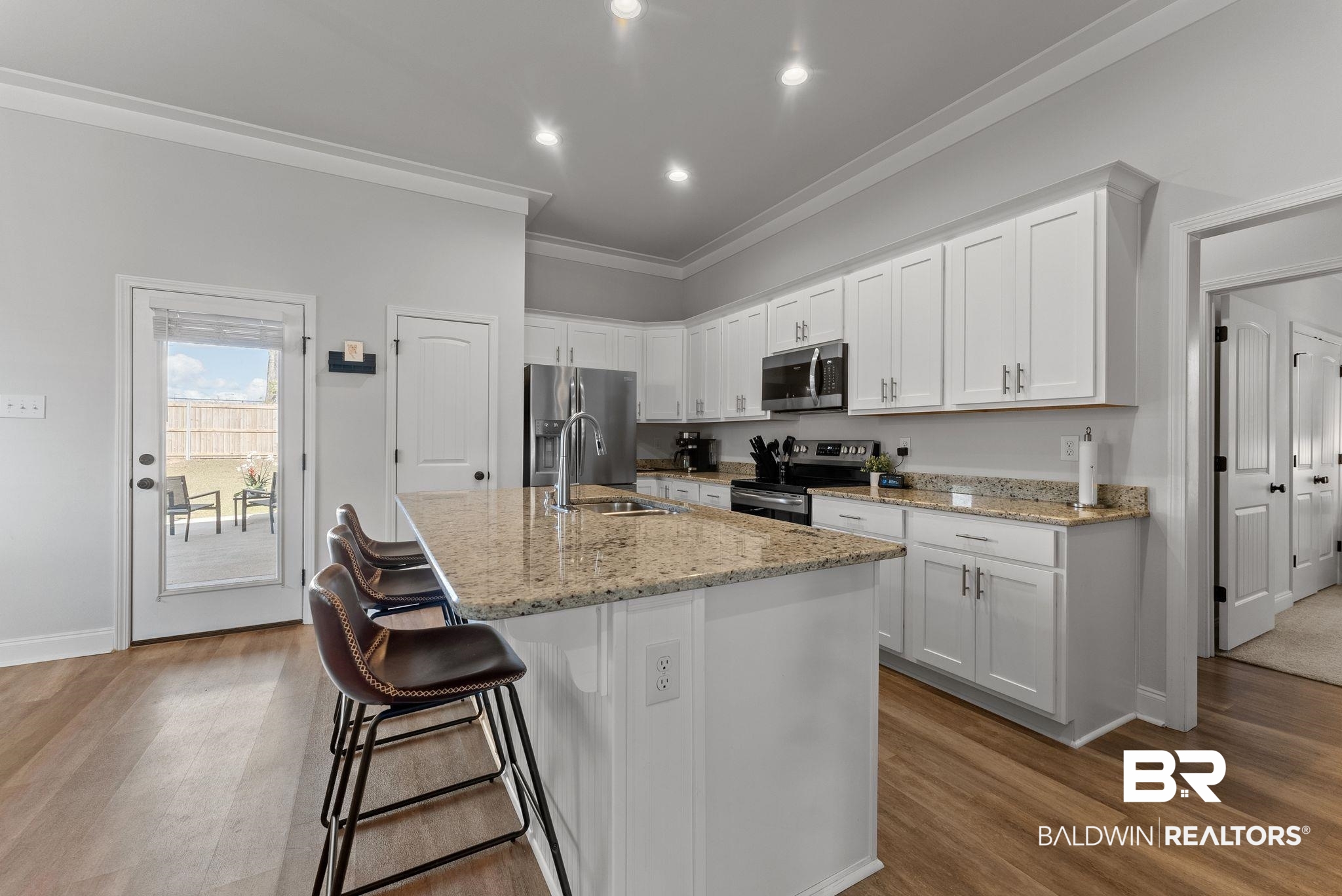 10745 Brodick Loop Daphne, AL 36527 - Photo 11 of 39 Kitchen featuring white cabinetry, a breakfast bar, stainless steel appliances, light stone countertops, and light wood-type flooring