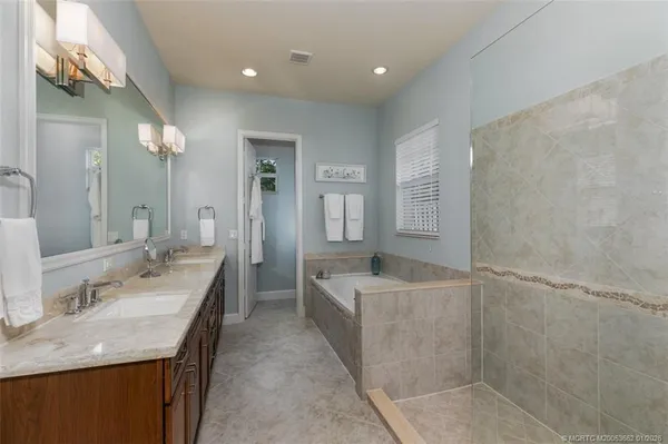 a spacious bathroom with a granite countertop sink a mirror and a bathtub