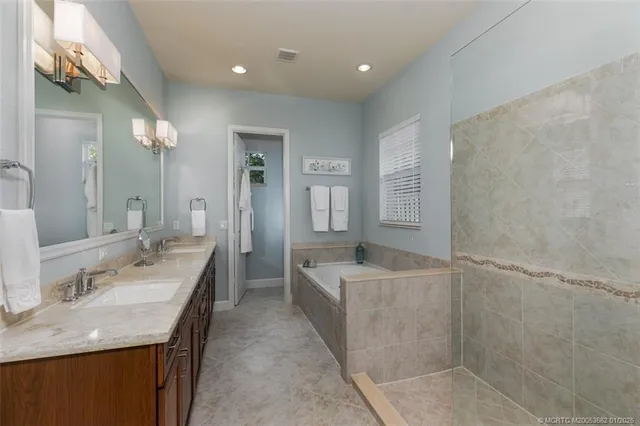 a spacious bathroom with a granite countertop sink a mirror and a bathtub