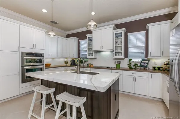 a kitchen with kitchen island granite countertop a sink counter top space appliances and cabinets