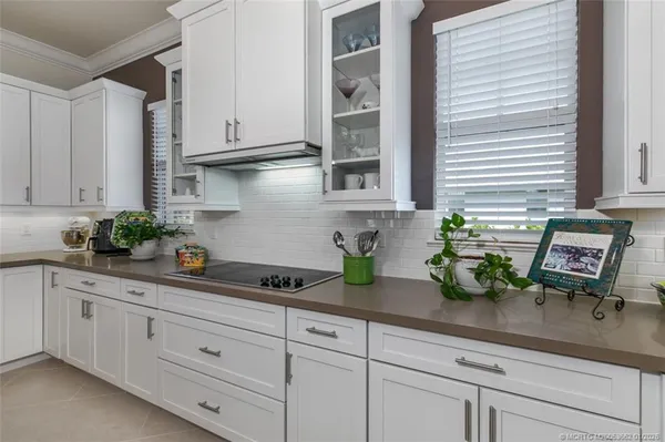 a kitchen with white cabinets and plant