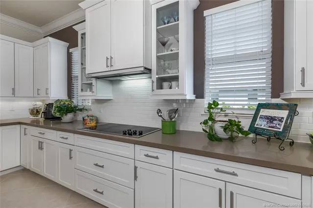 a kitchen with white cabinets and plant