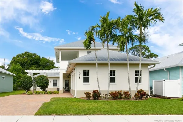 a view of a white house with a yard and potted plants