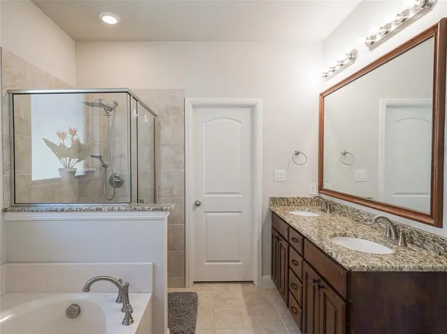a bathroom with a granite countertop tub sink and mirror