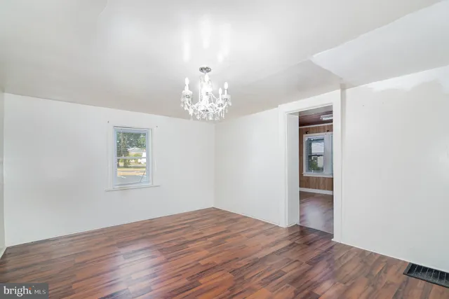 a view of a room with wooden floor chandelier and window