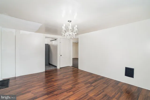 a view of a hallway with wooden floor and chandelier