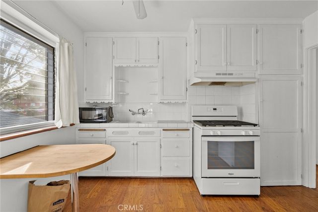 a kitchen with white cabinets appliances and wooden floor