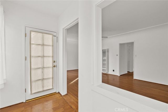 a view of an empty room with wooden floor and closet