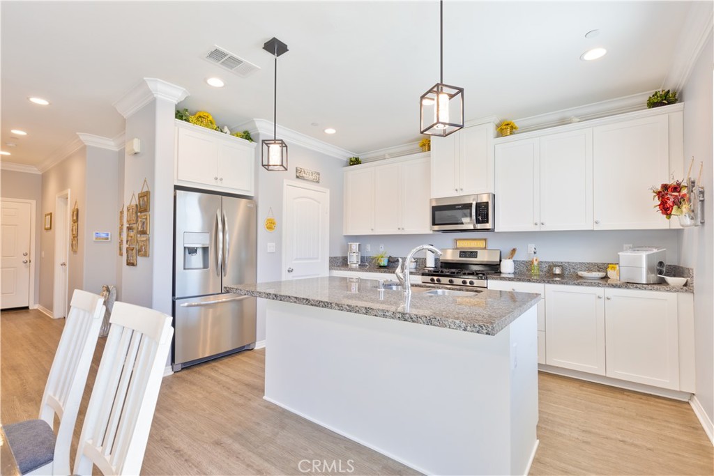 30283 Ramsay Drive Menifee, CA 92584 - Photo 5 of 24 a kitchen with stainless steel appliances granite countertop a refrigerator a sink dishwasher a stove and white cabinets with wooden floor