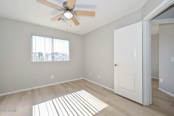 an empty room with a ceiling fan and wooden floor
