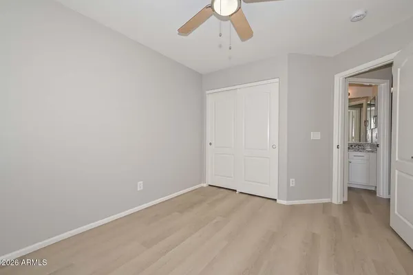an empty room with a chandelier fan and windows