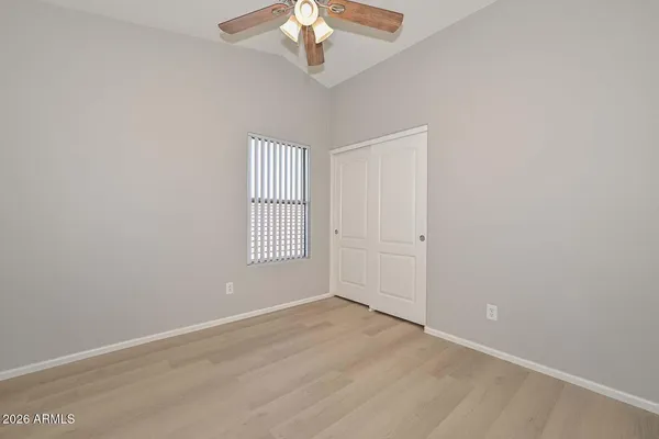 an empty room with a chandelier fan and wooden floor