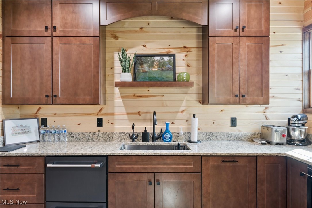 290 Townline Road Aurora, OH 44202 - Photo 17 of 50 Kitchen featuring dishwashing machine, light stone countertops, wood walls, brown cabinetry, and open shelves
