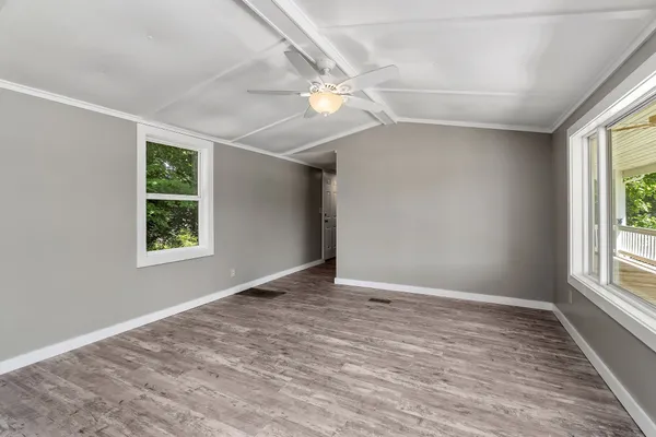a view of an empty room with wooden floor and a window