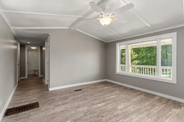a view of an empty room with a window and wooden floor