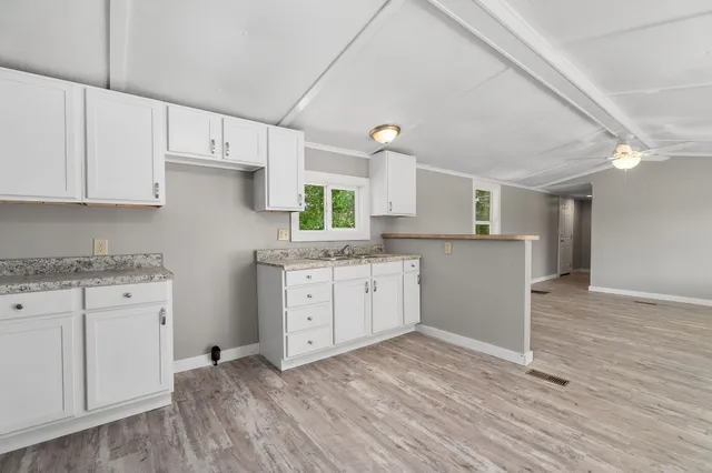 a kitchen with granite countertop white cabinets and white appliances