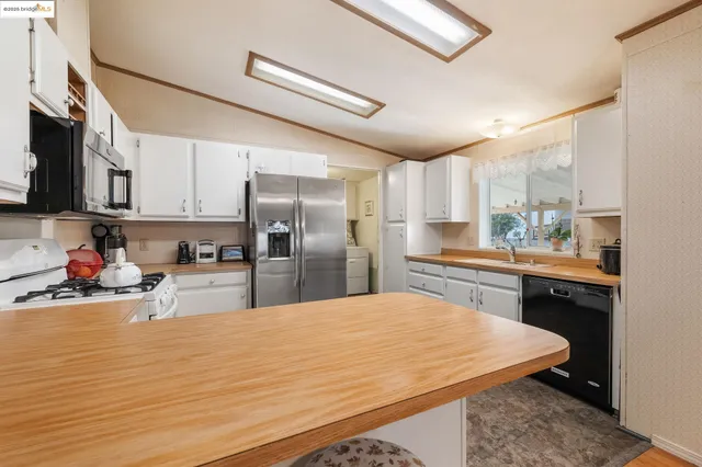 a kitchen with stainless steel appliances kitchen island granite countertop a refrigerator and a stove top oven