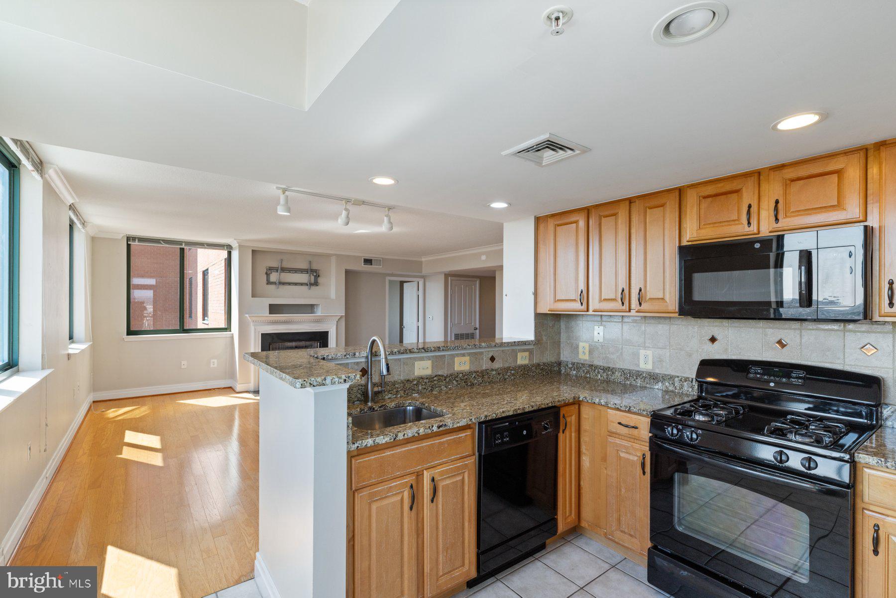 414 Water Street, Unit 2512 Baltimore, MD 21202 - Photo 7 of 40 a kitchen with stainless steel appliances granite countertop a stove top oven a sink dishwasher a dining table and chairs with wooden floor