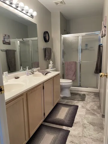 a bathroom with a double vanity sink toilet and shower