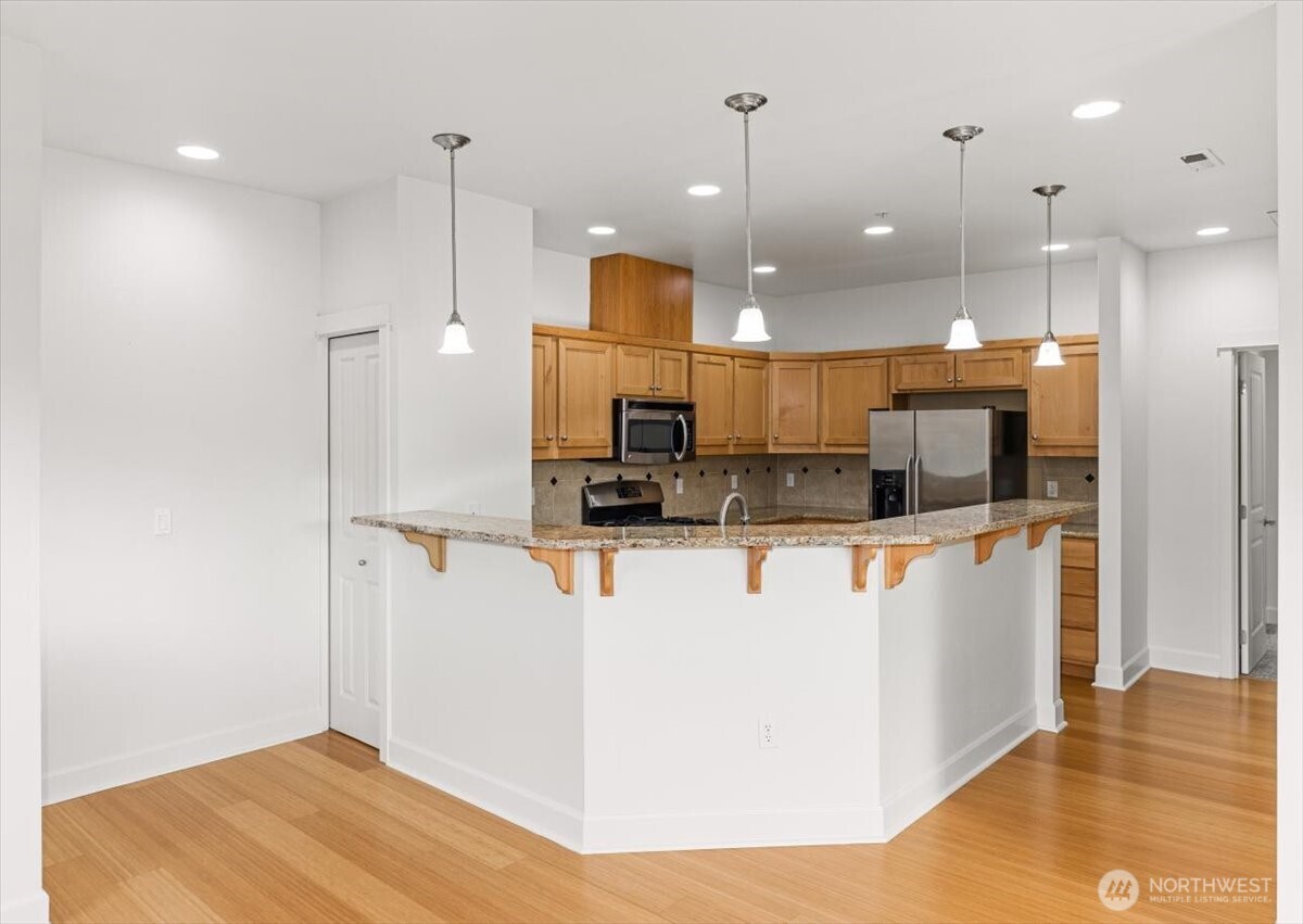 19102 20th Drive Southeast, Unit B206 Bothell, WA 98012 - Photo 15 of 39 a large kitchen with stainless steel appliances kitchen island a refrigerator and a wooden floor