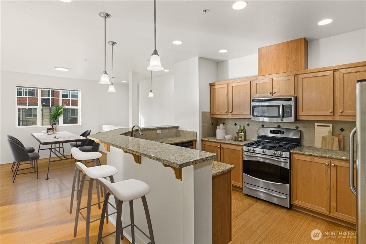 19102 20th Drive Southeast, Unit B206 Bothell, WA 98012 - Photo 20 of 39 a kitchen with stainless steel appliances granite countertop a stove top oven a sink dishwasher a dining table and chairs with wooden floor