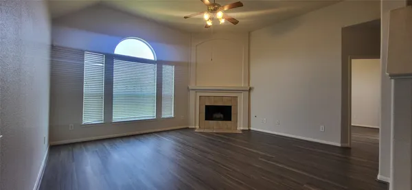 an empty room with wooden floor chandelier and windows