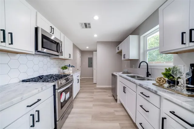 a large kitchen with stainless steel appliances granite countertop a stove a sink dishwasher and a microwave