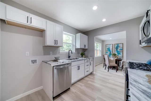 a kitchen with a stove a sink and white cabinets with wooden floor