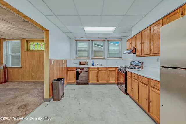 a utility room with stainless steel appliances granite countertop a refrigerator and a sink