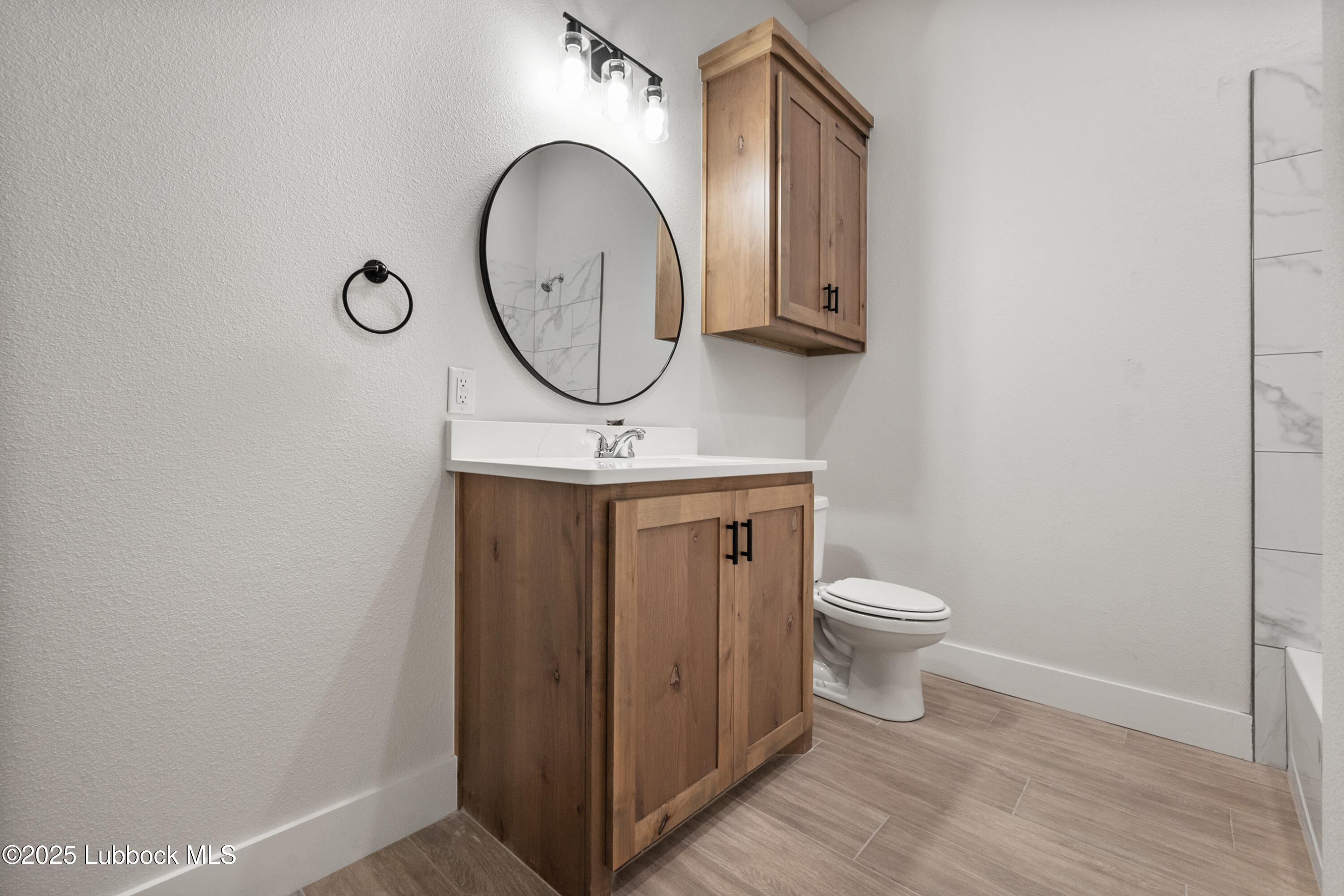7526 57th Street Lubbock, TX 79407 - Photo 32 of 36 a bathroom with a toilet a sink and a mirror