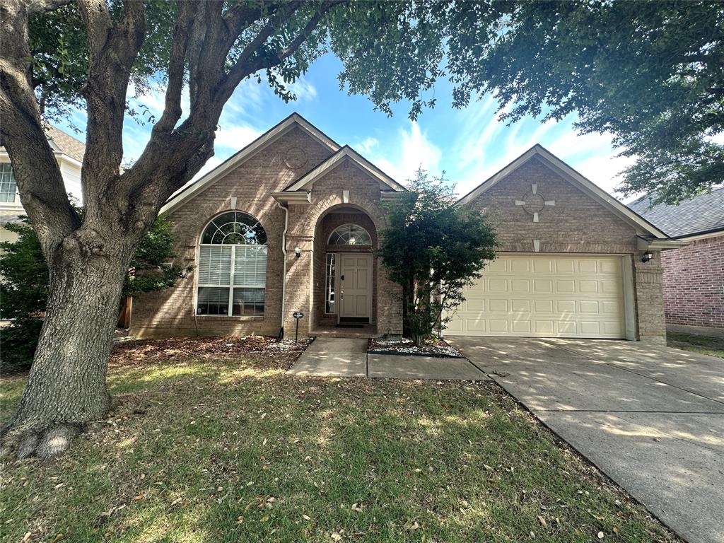 a view of a house with a yard and large tree