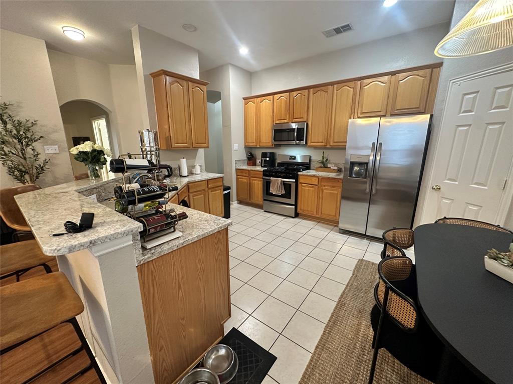2450 Streamside Court Frisco, TX 75036 - Photo 13 of 28 a kitchen with a refrigerator a stove a sink dishwasher and wooden cabinets