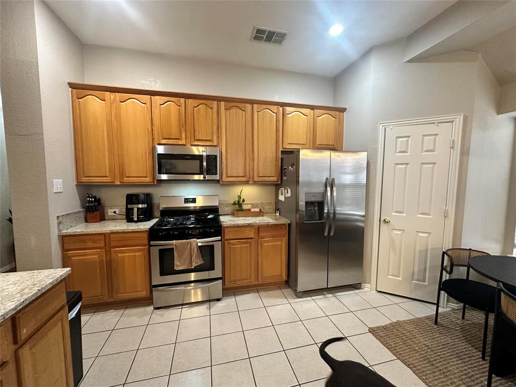 2450 Streamside Court Frisco, TX 75036 - Photo 14 of 28 a kitchen with a stove a microwave and a refrigerator