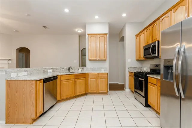 a kitchen with stainless steel appliances granite countertop a sink and dishwasher a refrigerator with wooden cabinets