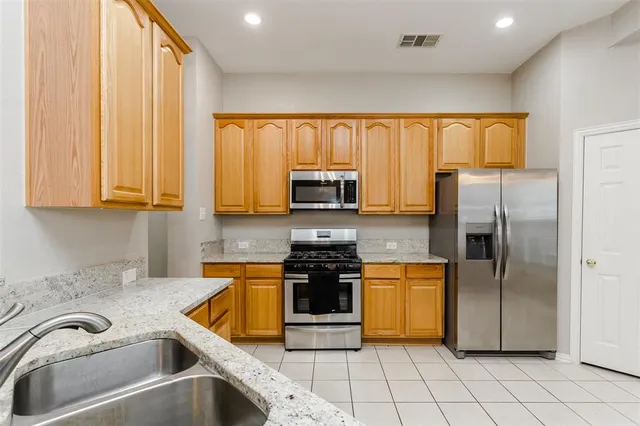 a kitchen with stainless steel appliances granite countertop a refrigerator and a stove top oven