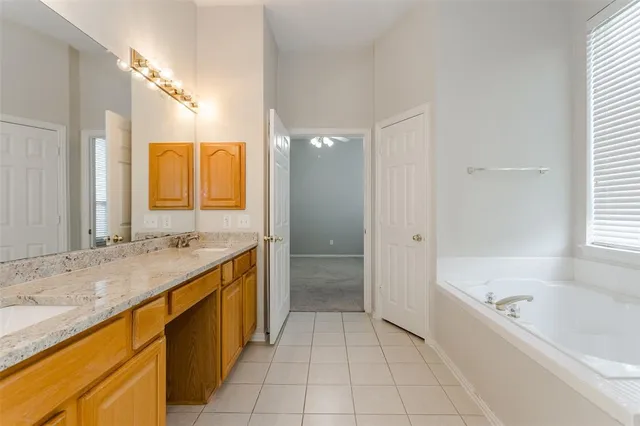 a spacious bathroom with a granite countertop sink a mirror and a bathtub