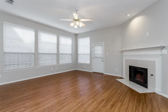 a view of an empty room with wooden floor and a fireplace