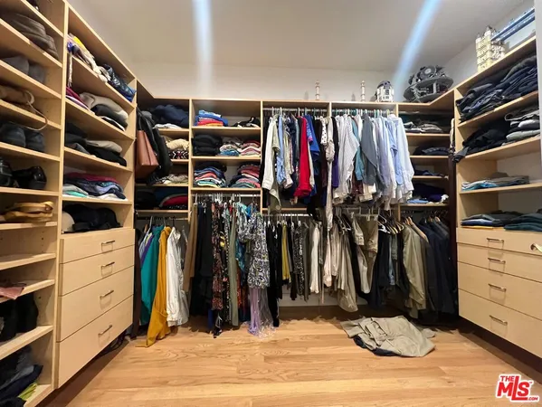 a view of walk in closet with clothes and shoes